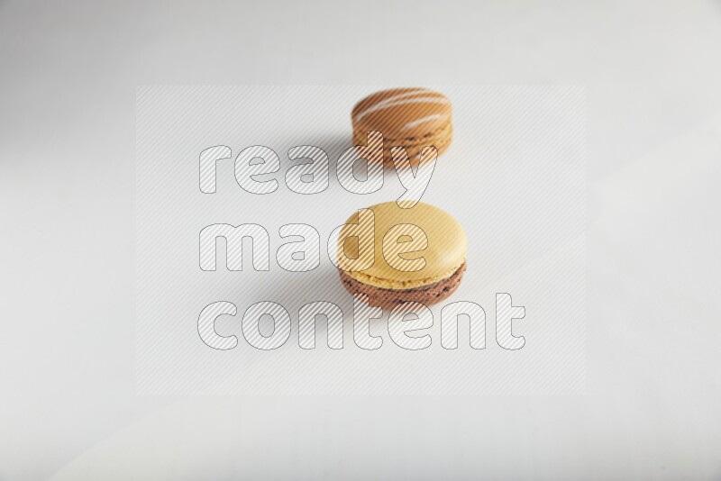 45º Shot of of two assorted Brown Irish Cream, and Yellow, and Brown Chai Latte macarons on white background