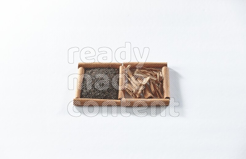 مربعان من أعواد القرفة ممتلئان بالشاي الأسود وقطع القرفة علي خلفية بيضاء