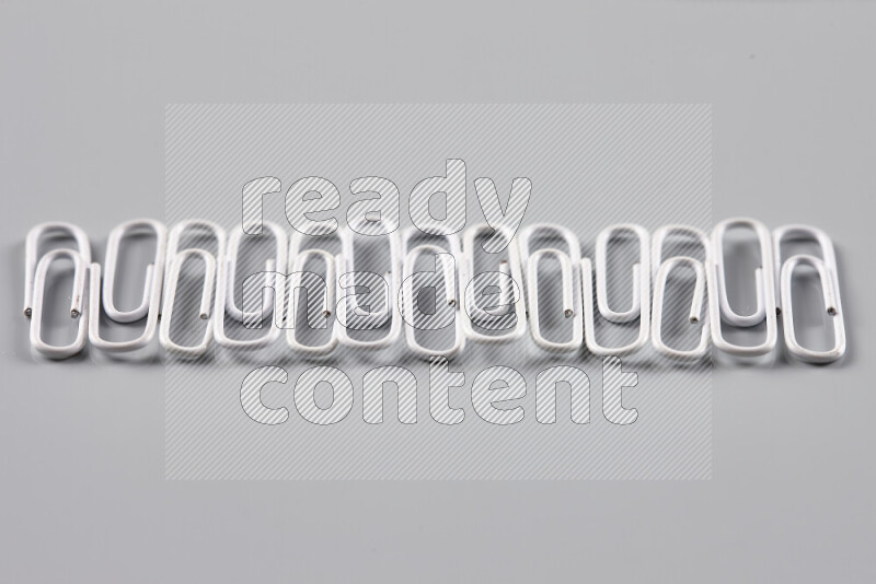 White paper clips isolated on a grey background
