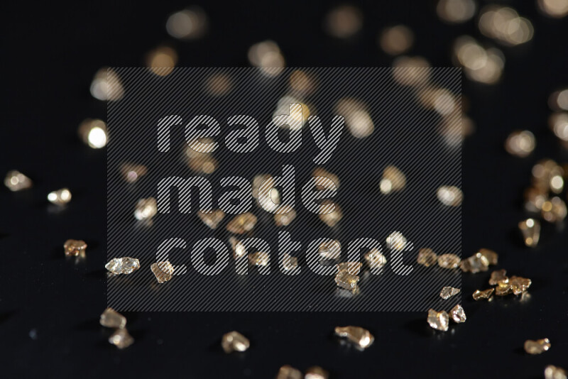 Gold shimmering fragments of glass scattered on a black background
