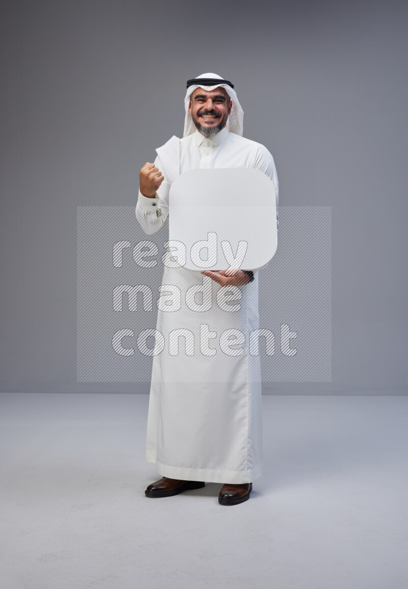 Saudi man Wearing Thob and white Shomag standing holding social media sign on Gray background