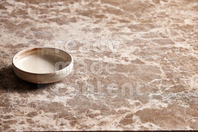 A beige pottery bowl on beige marble background