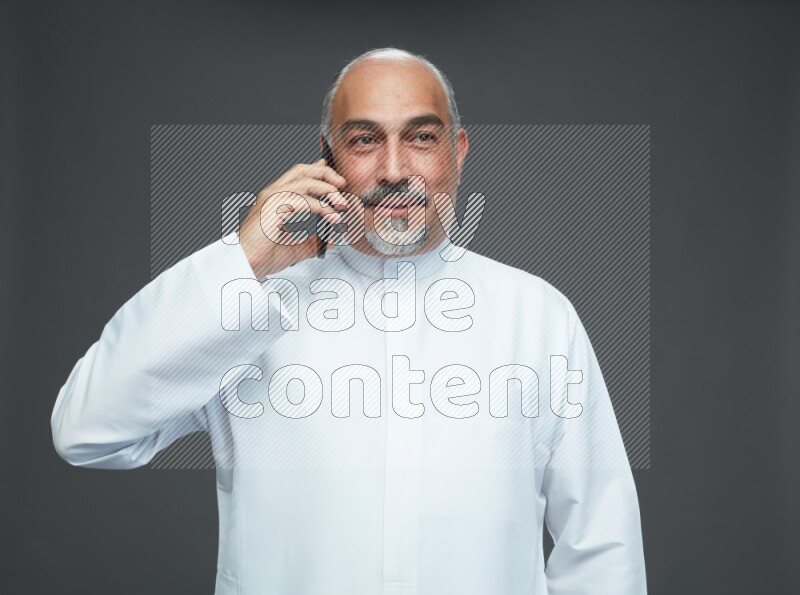 Saudi man without shomag Standing talking on phone on gray background