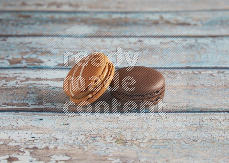45º Shot of of two assorted Brown Irish Cream, and Brown Dark Chocolate macarons on light blue background