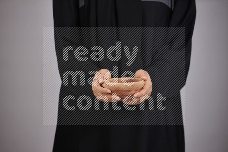 A woman in black abaya holding different wooden essentials in different positions