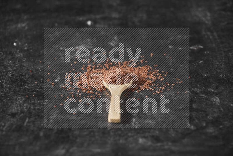 ملعقة خشبية ممتلئة ببذور حب الرشاد محاطه بالبذور علي خلفية سوداء