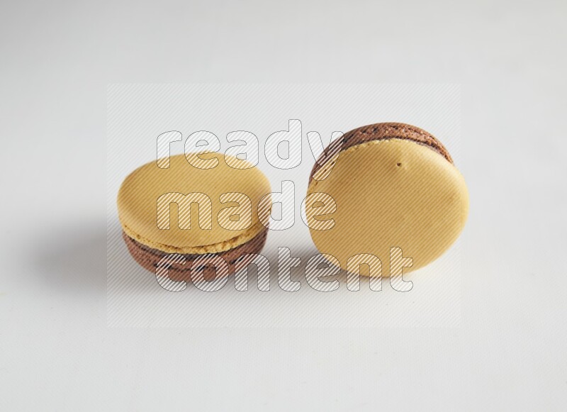 45º Shot of two Yellow and Brown Chai Latte macarons on white background
