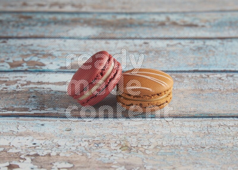 45º Shot of of two assorted Brown Irish Cream, and Red Velvet macarons on light blue background
