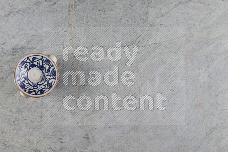 A multicolored pottery pot with its lid on grey marble background
