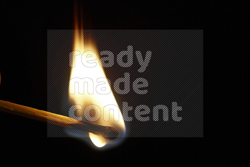 A burning matchstick isolated on dark backdrop