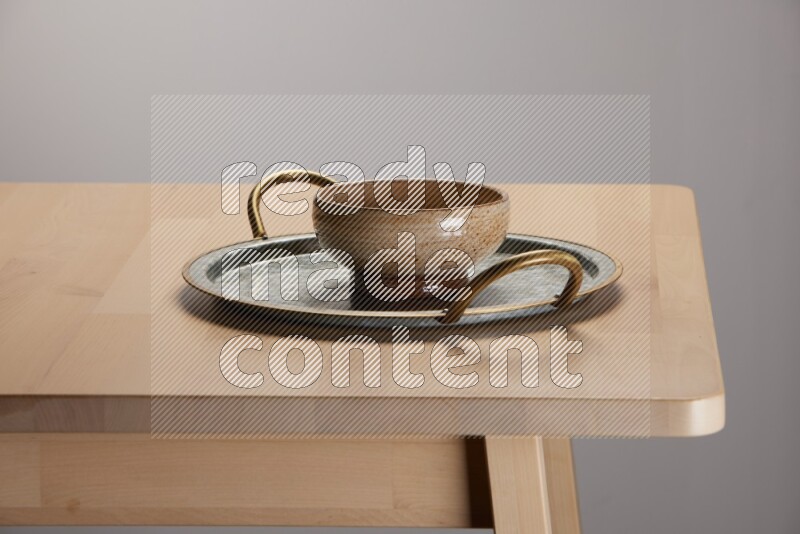 multicolored bowl placed on a rounded stainless steel tray with golden handels on the edge of wooden table