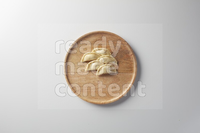 Five Sambosas on a wooden round plate on a white background