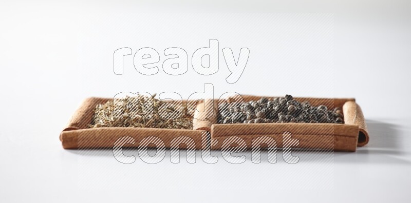 2 squares of cinnamon sticks full of black peppers and cumin on white flooring