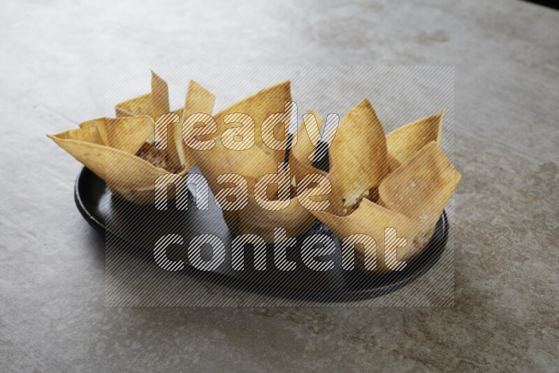 wonton cups on oval black ceramic plate on grey textured counter top