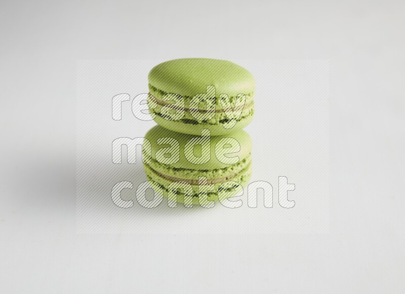 45º Shot of two Green Pistachio macarons on white background