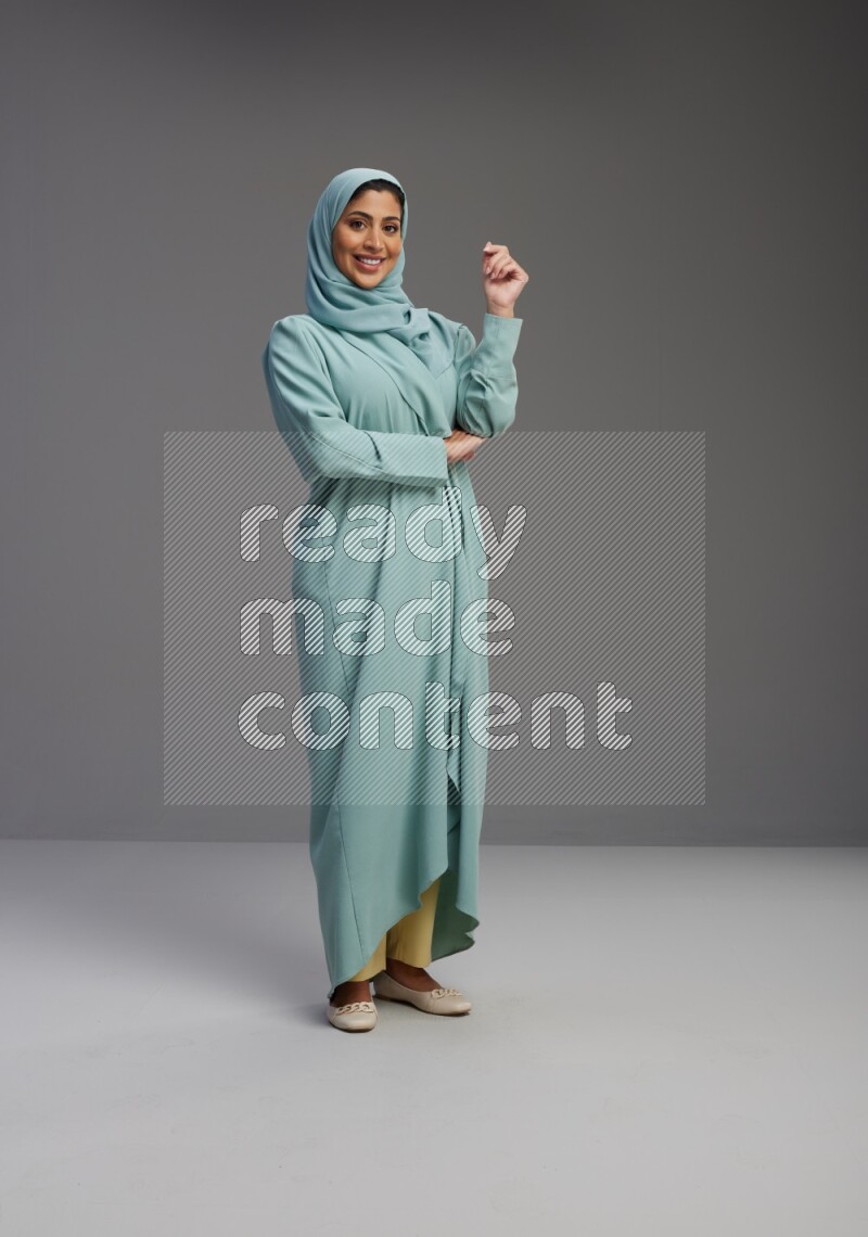 Saudi Woman wearing Abaya standing interacting with the camera on Gray background