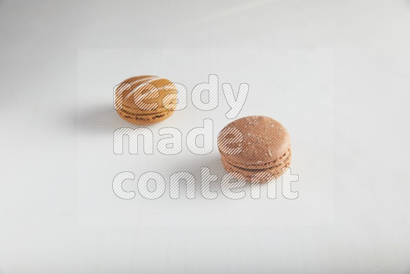 45º Shot of of two assorted Brown Irish Cream, and Brown Hazelnuts macarons on white background