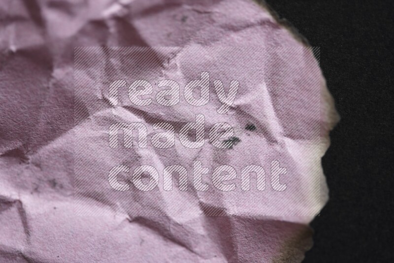 Burnt multicolored paper on black background