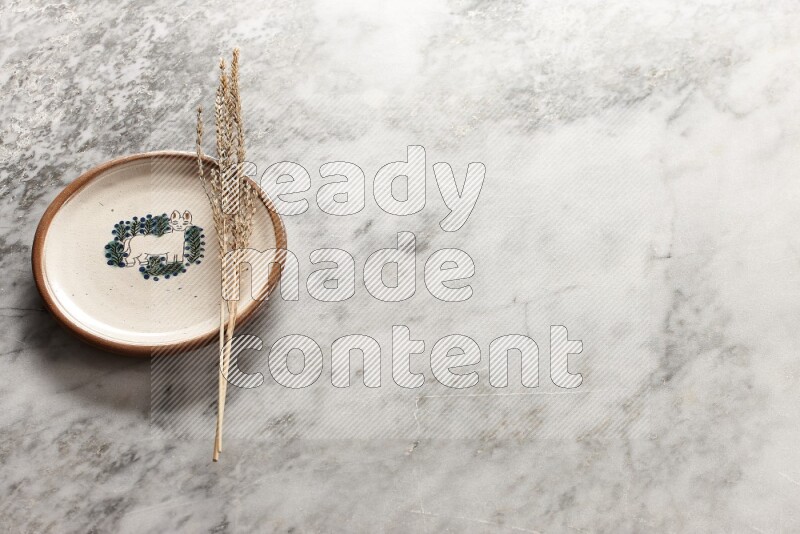 Wheat stalks on decorative pottery plate on grey marble background