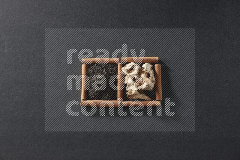 2 squares of cinnamon sticks full of dried ginger and black tea on black flooring