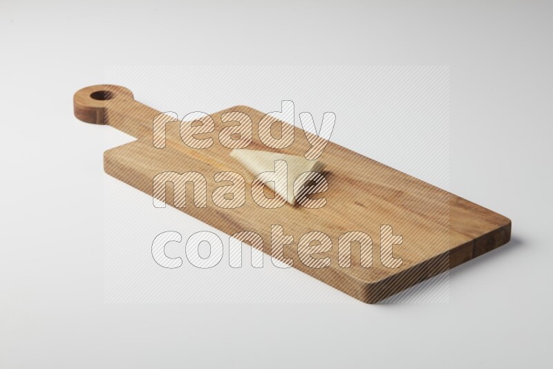One uncooked samosa on a wooden cutter on a white background