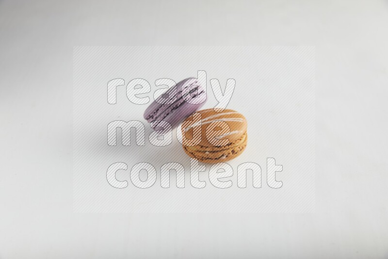 45º Shot of of two assorted Brown Irish Cream, and Purple Blueberry macarons on white background