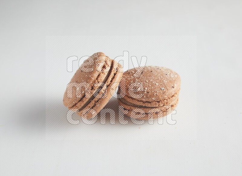 45º Shot of two Brown Hazelnuts macarons on white background