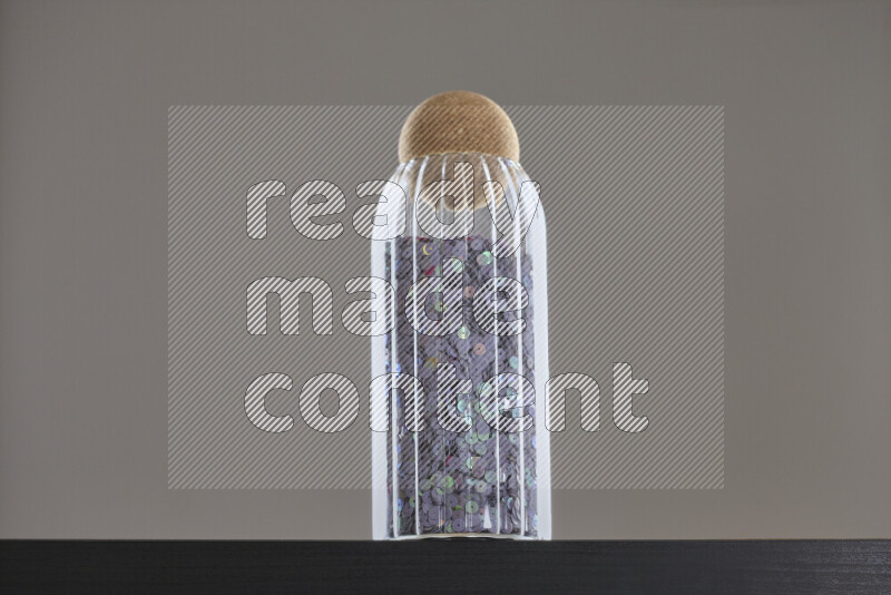 Sequins in a glass jar on black background