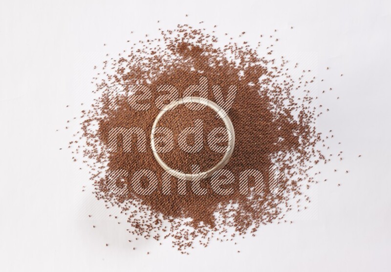 A beige pottery bowl full of garden cress seeds with more seeds spread on a white flooring