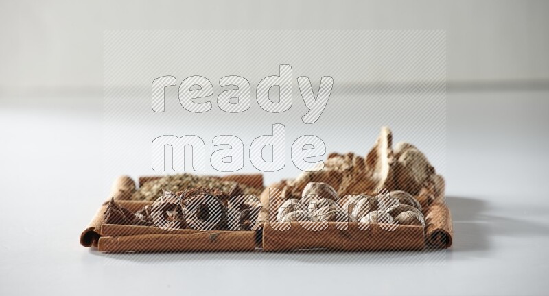 4 مربعات من أعواد القرفة ممتلئة باليانسون والزنجبيل والكمون وجوزة الطيب على أرضية بيضاء