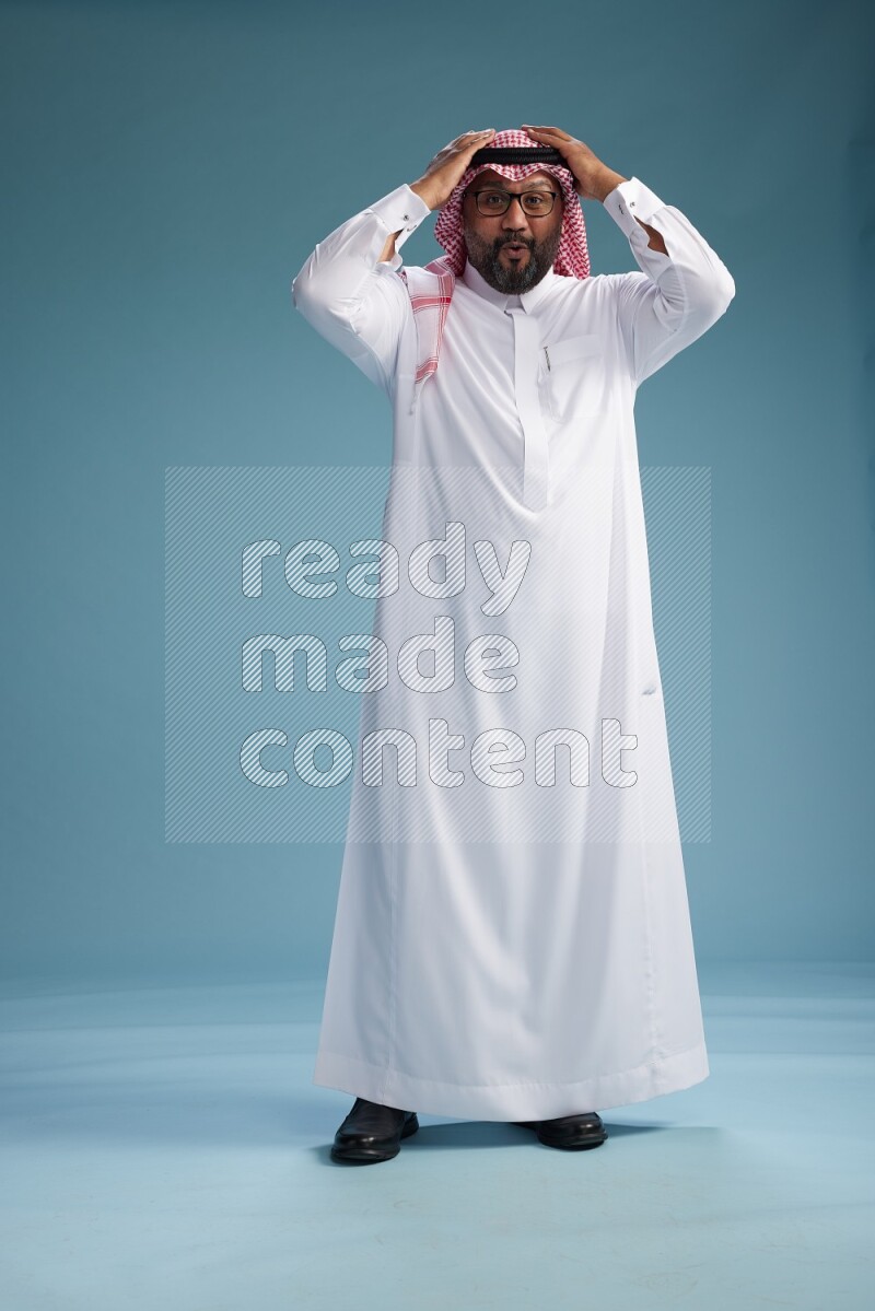 Saudi Man with shimag Standing Interacting with the camera on blue background
