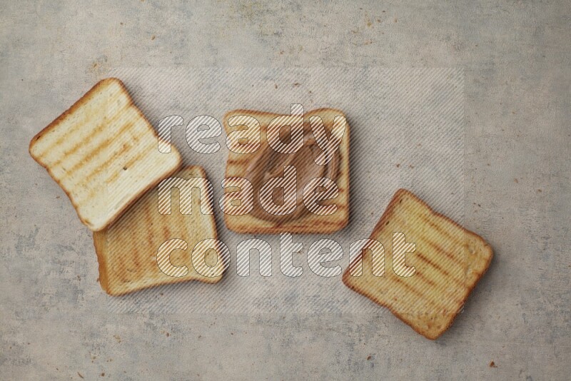 Creamy peanut butter on a toasted white toast and toasted white toast slices on a light blue textured background