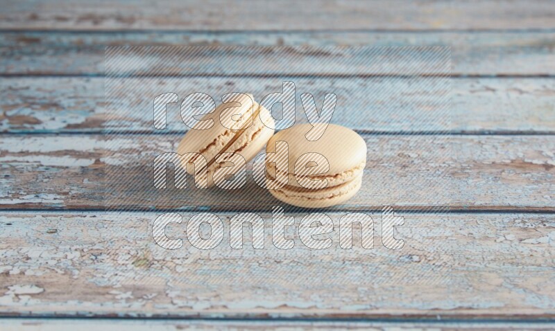 45º Shot of two White Caramel fleur de sel macarons on a light blue wooden background