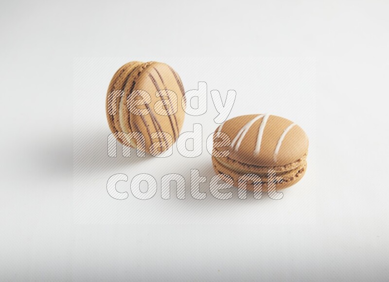 45º Shot of of two assorted Brown Irish Cream, and light brown  Almond Cream macarons on white background