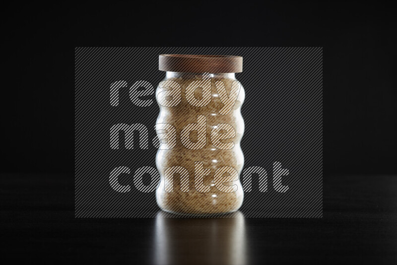 Basmati golden rice in a glass jar on black background