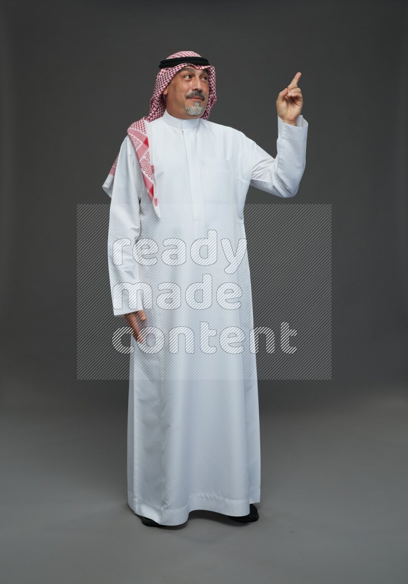 Saudi man with shomag Standing Interacting with the camera on gray background