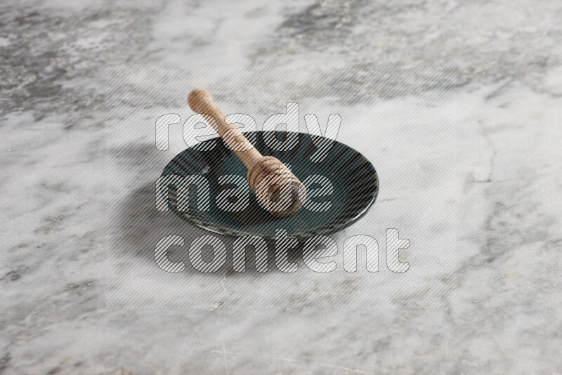 Multicolored pottery plate with wooden honey dipper in it on grey marble background