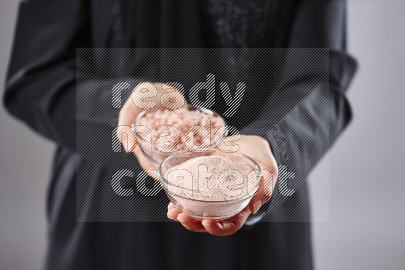 Woman in abaya holding different kinds of spices in different positions