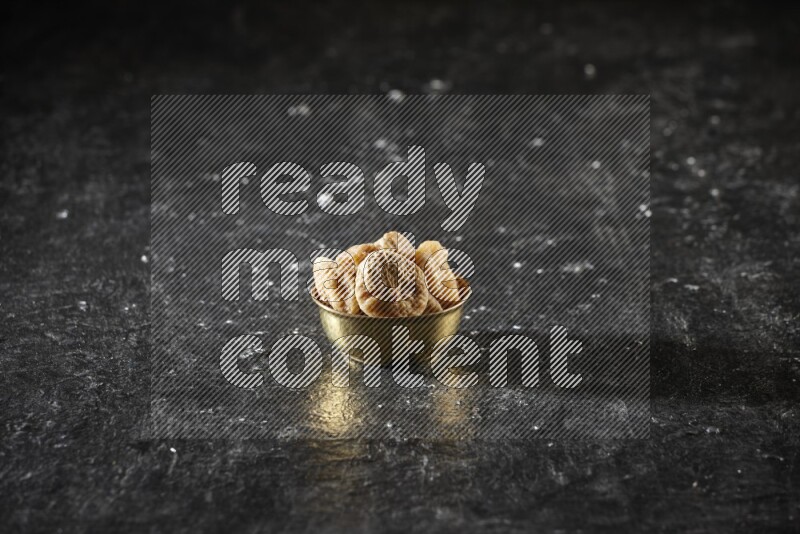 Dried fruits in a metal bowl in a dark setup