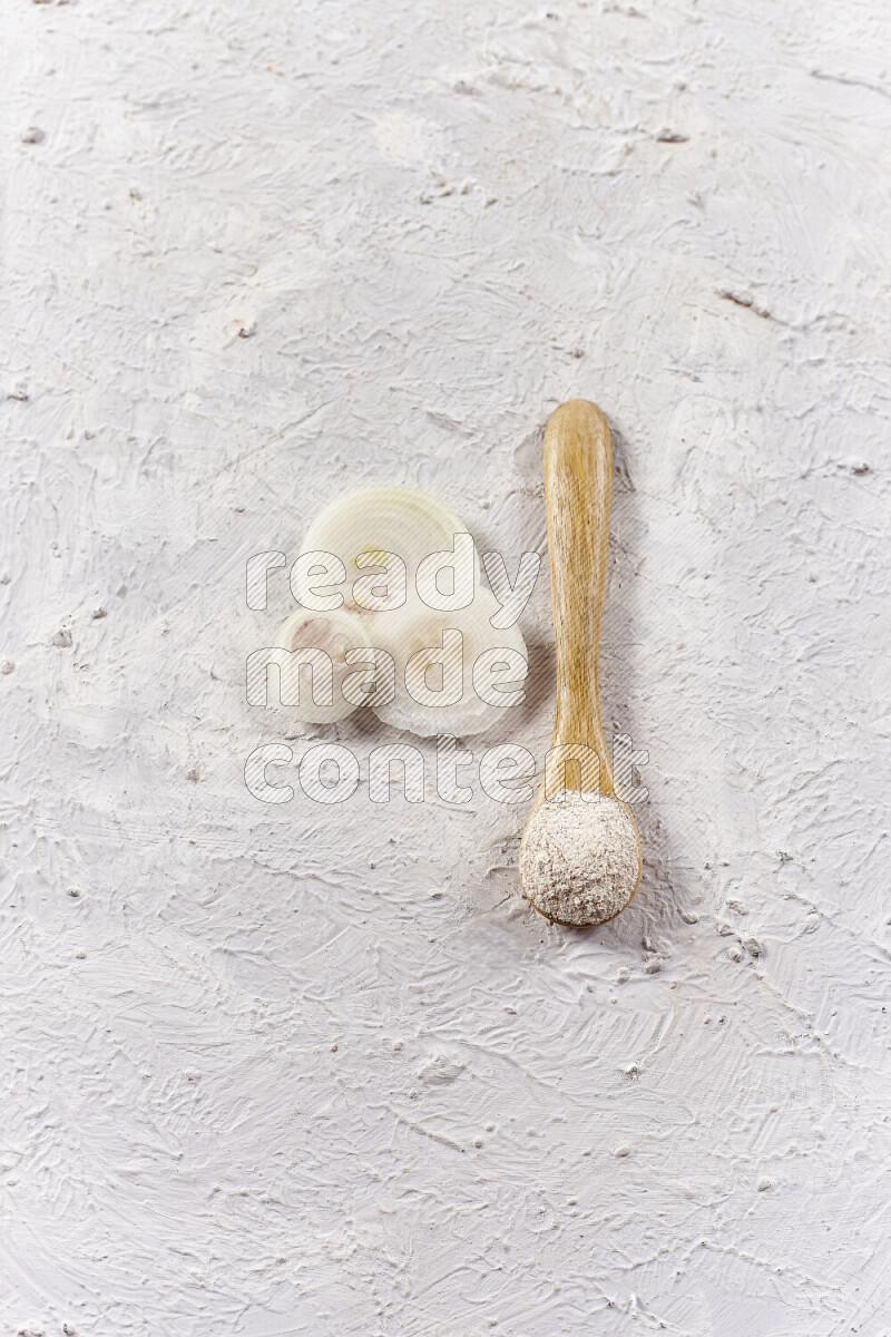 A wooden spoon full of onion powder on white background