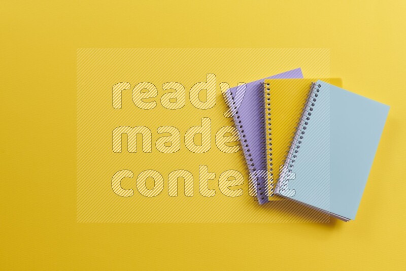 Multicolored notebooks on yellow background