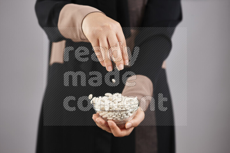 Woman in abaya holding different kinds of legumes in different positions