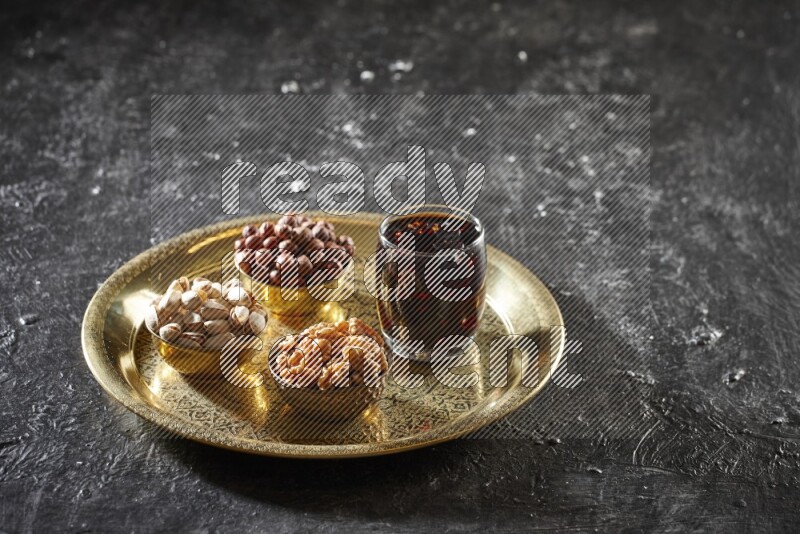 Nuts in metal bowls with tamarind on a tray in dark setup
