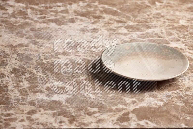 A multicolored pottery plate on beige marble background