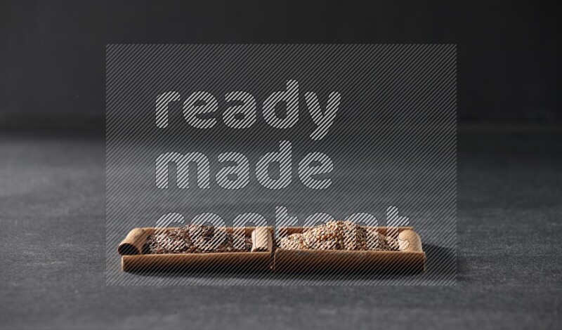 مربعان من أعواد القرفة ممتلئان بحبوب الخردل وبذور الكتان علي خلفية سوداء