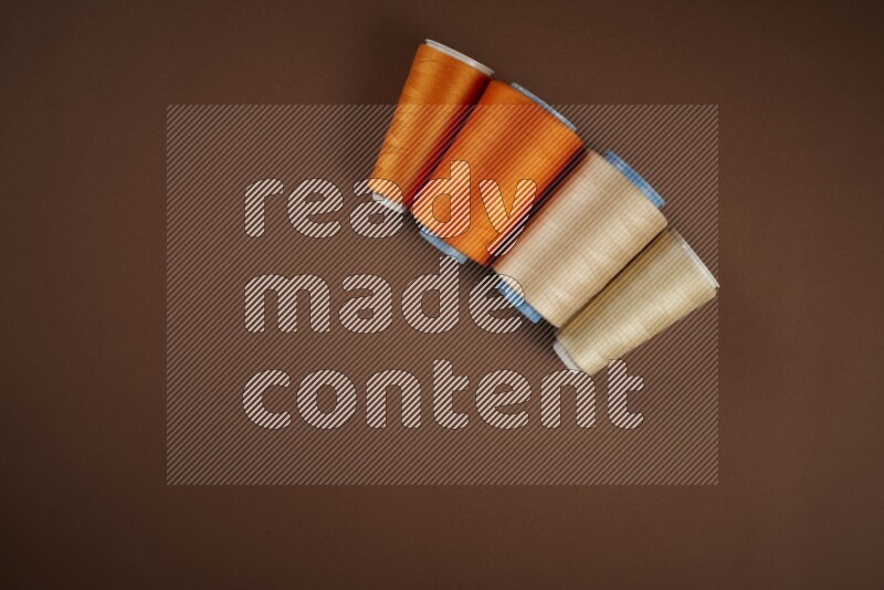 An orange collection of sewing and tailoring tools arranged on a brown background