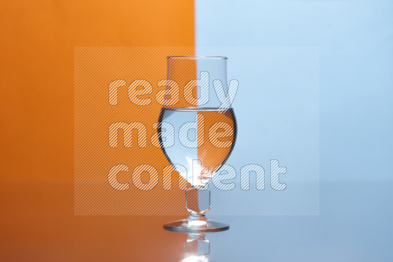 The image features a clear glassware filled with water, set against orange and light blue background