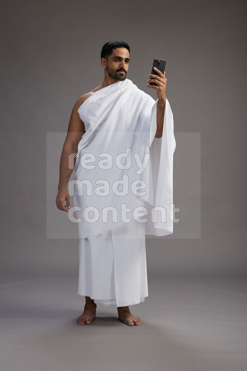 A man wearing Ehram Standing taking selfie on gray background