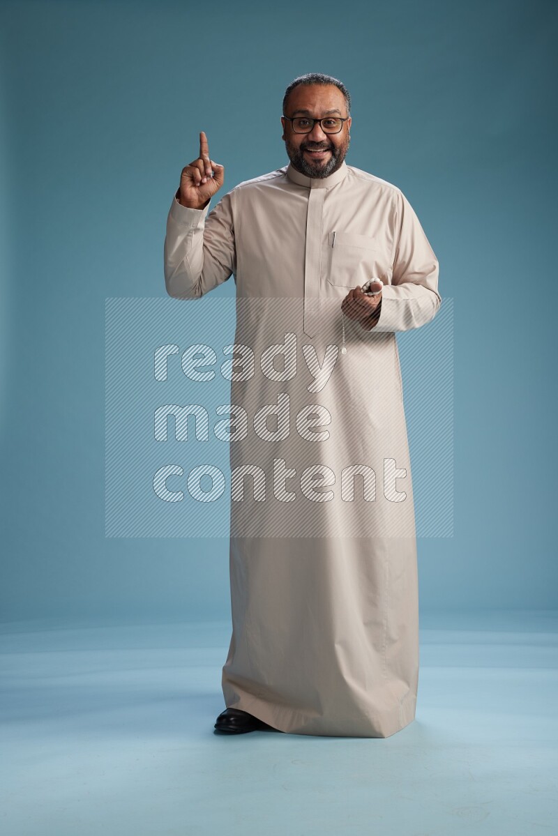 Saudi Man without shimag Standing Interacting with the camera on blue background