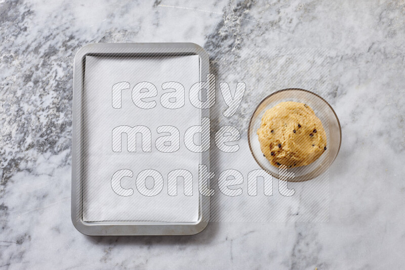 Cookies step by step with its ingredient, flour, butter, brown sugar, egg, vanilla extract, white sugar, chocolate chips and baking soda on grey marble background